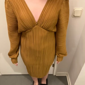 Gul plisserad klänning - Säljer en superfin senapsgul klänning med plisserad design. Den har en djup v-ringning och långa ärmar. Perfekt för hösten och våren. I stl xs, endast testad men prislapp kvar. Köpt för 450 från vero moda och säljer för 250 men kan gå ner i pris💛 Skriv för fler bilder och övriga frågor!