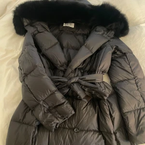 Svart pälsjacka  - Svart dunjacka med luva och pälskrage. Storlek S men passar även xs. Håller värme. Köpt från fur Stockholm 