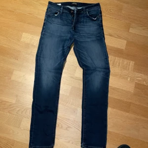 Mörkblå jeans från Jack & Jones - Snygga mörkblå jeans från Jack & Jones i modellen Slim Glenn. De har en slim passform och klassisk femficksdesign med dragkedja. Perfekta för en stilren look. Storlek: 29/32