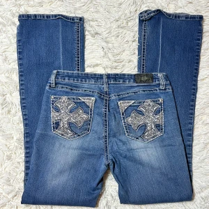 Lågmidjade bootcut jeans med kors  - Lågmidjade bootcut jeans med kors på bakfickorna. Storlek ”11” skulle säga att detta motsvarar en stor s eller m. Innerbenslängd: 80 midjemått:40. Har inga bilder på då de är för stora. Köp sker via köp nu, jag postar inom 24h. Kvar tills markerad såld 