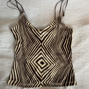 Mönstrad topp från Naf Naf - Snygg topp från Naf Naf med geometriskt mönster i brun och beige. Toppen har smala axelband och en v-ringad design, perfekt festtopp.