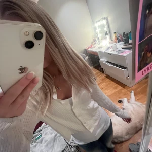 Vit ribbad kofta - Säljer en stilren vit ribbad kofta med knappar framtill. Koftan har långa ärmar och en v-ringad design, perfekt för lager-på-lager-stil. Passar både till jeans och kjol för en avslappnad look.