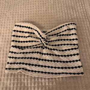 Randig tubtopp - Snygg randig tubtopp i svart och beige med en knutdetalj framtill. Perfekt för sommardagar eller en ute kväll. Tillverkad i ett mjukt och bekvämt material. Från new yorker. St XL men är väldigt liten i storleken så den passar S och M mer skulle jag säga( jag själv har S och M vanligtvis)