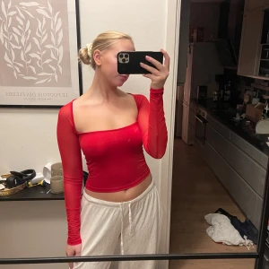Röd långärmad offshoulder topp - Snygg röd offshoulder topp med långa ärmar. Den är croppad och har en tight passform, perfekt för en kväll ute! Stretchiga i materialet, genomskinlig i ärmarna 