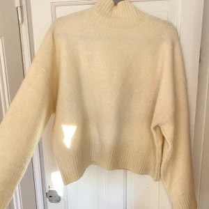 Beige stickad tröja från Zara - Säljer en mysig beige stickad tröja från Zara. Tröjan har en hög krage och långa ärmar med ribbade muddar. Perfekt för kyliga dagar! lite nopprig, men funkar!