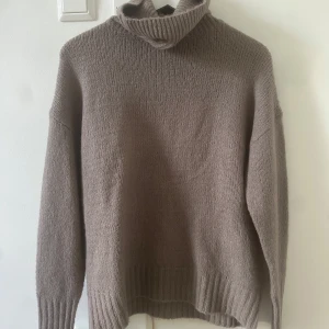 Beige stickad polotröja - Mysig beige stickad polotröja med långa ärmar och ribbstickade muddar. Perfekt för kyliga dagar.