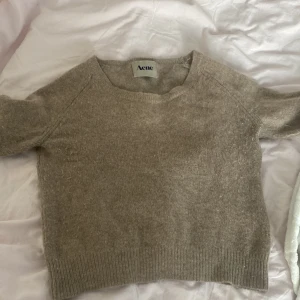 Beige stickad tröja från Acne - Säljer en stilren beige stickad tröja från Acne. Tröjan har en rund halsringning och korta armar💖