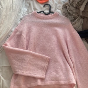 Rosa tröja från Gina Tricot - Mysig rosa tröja från Gina Tricot i premiumkvalitet. Perfekt för kyligare dagar med sin mjuka och bekväma design. Tröjan har långa ärmar och en klassisk rund halsringning.