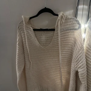 Beige stickad hoodie - Mysig beige stickad hoodie med luva och dragsko. Tröjan har en avslappnad passform och långa ärmar. En populär hoodie för ett tag sen som är använd fåtal gånger men inga defekter. Skicka för frågor😊