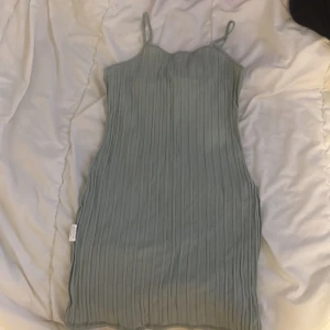 Grön ribbad klänning - Snygg grön ribbad klänning med smala axelband. Perfekt för en stilren och enkel look. Klänningen har en figurnära passform och är tillverkad i ett mjukt material.