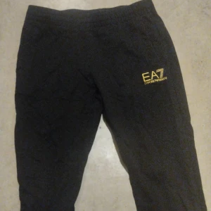 Svarta mjukisbyxor från EA7 Emporio Armani - Snygga svarta mjukisbyxor från EA7 Emporio Armani med elastisk midja och gul logga på sidan. Perfekta för en avslappnad stil.
