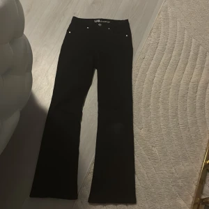 Svarta byxor från LAB - Snygga svarta byxor från LAB med bootcut-stil. Perfekta för en stilren look. Byxorna har en hög midja och är tillverkade i ett stretchigt material för extra komfort.