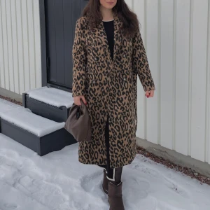 Leopardmönstrad kappa 38 nyskick  - Snygg leopardmönstrad kappa med långa ärmar. Perfekt för att göra ett statement i vinterkylan. Kappan har en klassisk passform och är ett måste för garderoben.