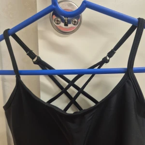 Svart träningslinne XS - Med inbyggd bh, ej uttagbar vaddering. Tillverkad av 80% polyamid och 20% elastan för en stretchig och bekväm passform. Helt ny, aldrig använd. 