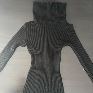 Svart ribbad långärmad tröja - Snygg svart ribbad tröja med ned vik var krage. Väldigt fin i många olika stilar!  