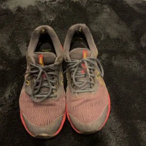 Asics Gel Pulse 11 löparskor - Säljer ett par Asics Gel Pulse 11 löparskor i grått med röda och gula detaljer. Skorna har snörning och är tillverkade i Gore-Tex-material för extra skydd mot väta. Perfekta för löpning och träning.