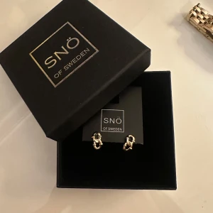 Guldörhängen från Snö of Sweden - Snygga guldörhängen från Snö of Sweden i en elegant design. Perfekta för att ge en touch av stil till vilken outfit som helst. Kommer i originalförpackning.