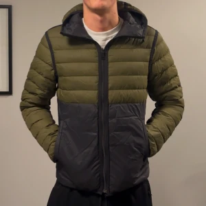 J.Lindberg dunjacka reversible  - Säljer denna snygga tunna dunjacka från J.Lindeberg! Jackan är reversible så man kan både ha den som grön/svart rller helsvart, dock har den en lagning på den svarta sidan, alltså syns lagningen inte om man har den åt de grön/svarta hållet! Utöver det så är jackan i bra skick! Passar M. Modellen på bilden är 182cm lång ish. Skriv vid funderingar!