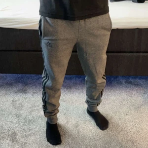 Grå mjukisbyxor från Adidas - Snygga grå mjukisbyxor från Adidas. Byxorna är gamla och köpta ifrån Stadium. Dom är använda ett par gånger men är i mycket bra skick. Storlek på mjukisbyxorna är 36/S. 