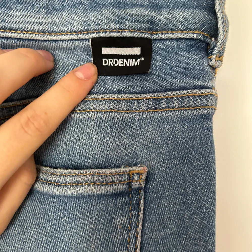 Säljer ett par snygga blå bootcut jeans från Dr. Denim i storlek S/34. De har en klassisk fyrficksdesign och är perfekta för både vardag och fest. Jeansen är i bra skick och har en skön passform som sitter snyggt över höfterna och vidgar sig vid benen. Nypris 700kr. Jeans & Byxor.