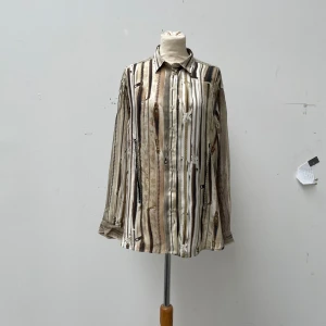 Jean Paul Gaultier x Lindex Tromp-l’œil zipper shirt - Beautiful shirt designed by Jean Paul Gaultier for Lindex. Features a Trompe-l’œil print of multiple zippers as well as a real front zipper that lets you cinch the waist. A womens size but I have worn it as a unisex garment No damages to the garment.