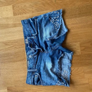 Blå jeansshorts med slitningar - Säljer ett par snygga blå jeansshorts med coola slitningar och broderade detaljer. De är perfekt för sommaren och har en lågmidjad passform. Shortsen har en klassisk femficksdesign och stängs med knapp och dragkedja. De är små i storleken, från Ralph Louren. Priset går att diskutera, kontakta om du har frågor eller vill ha fler bilder💗💗