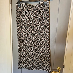 Blommig långkjol - Blommig långkjol i svart med vita och bruna blommor. Normal passform. Den är i nyskick då den knappt använts. Storlek M, men sitter bra på mig som har XS/S