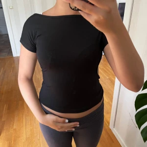 Svart tight topp - Säljer en svart tight topp i storlek S. Den är kortärmad och har en öppen rygg. Perfekt för både vardag och fest! 🖤