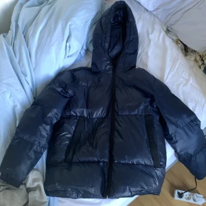 Svart pufferjacka från Emporio Armani - Säljer en snygg svart pufferjacka från Emporio Armani, perfekt för kalla dagar. Jackan har en huva och dragkedja framtill. Den är i bra skick och håller dig varm och stilren under vintern. priset kan diskuteras 