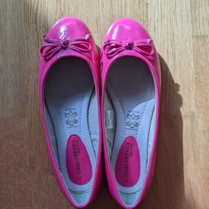 Rosa ballerinaskor - Skrikrosa ballerinaskor i strl. 37 med innersula i läder och syntetisk ytterdel. Använts max 5 gånger eftersom de är för små för mig. Liten skada då ytskiktet släppt på några platser (se bild 3 längst bak på skon och fram), men knappt märkbart.