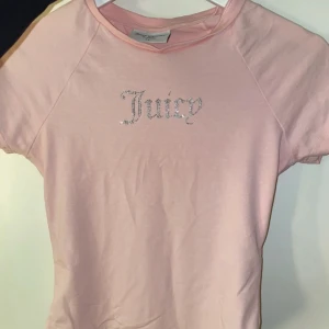 Juicy Couture T-shirt - Rosa juicy couture T-shirt, ganska tight i modellen m korta ärmar. Silvrigt strass på bröstet. Använd 1 gång.
