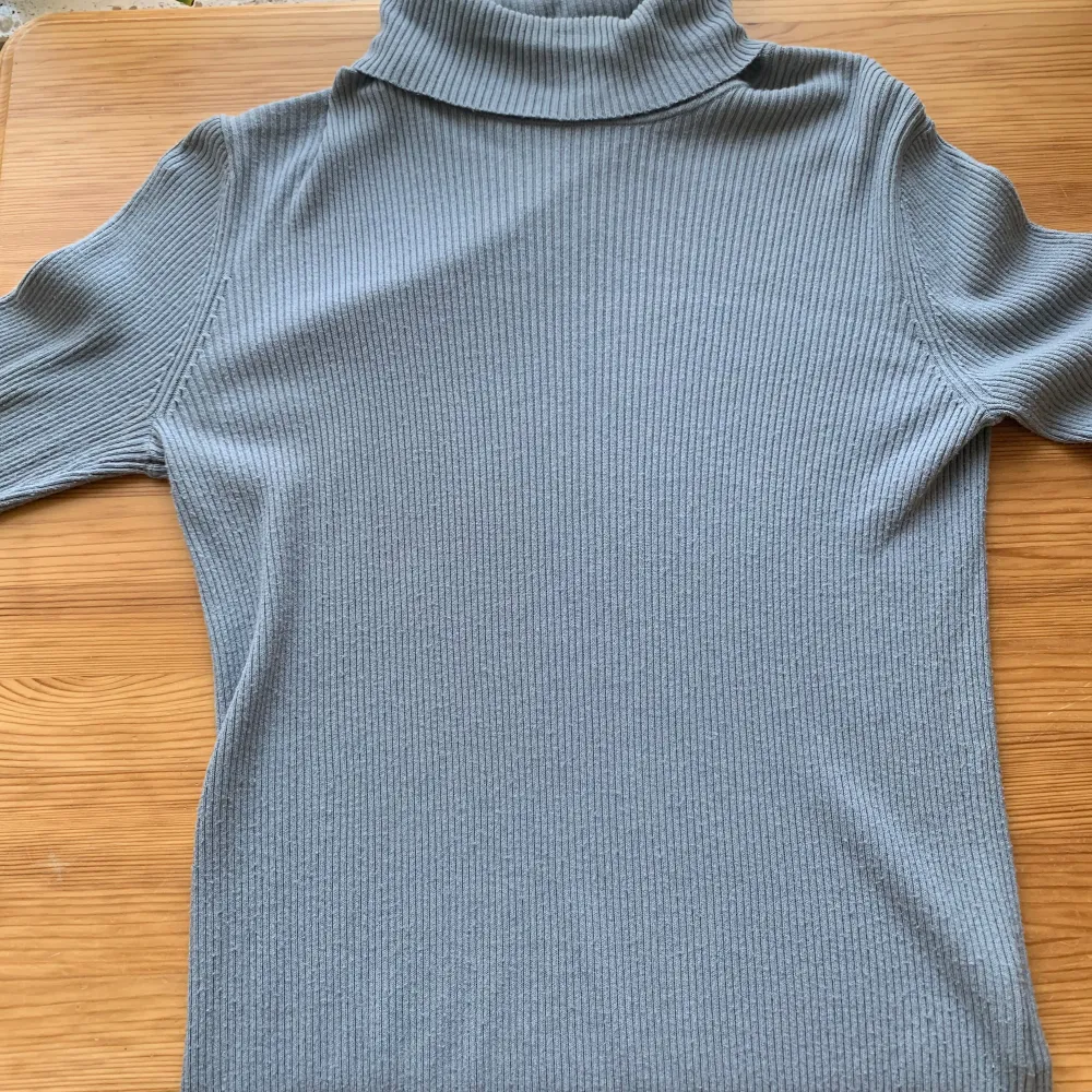 Säljer en stilren och bekväm grå polotröja från H&M. Den är ribbad och har långa ärmar, perfekt för höst och vinter. Tröjan är i bra skick och passar både till vardags och lite finare tillfällen. Supermjuk och skön att ha på sig!. Neuletakit & Villapaidat.