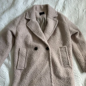 Beige teddyjacka från Bershka - Säljer en supermysig beige teddyjacka från Bershka. Den har en klassisk krage och två knappar framtill. Perfekt för höst och vinter när du vill hålla dig varm och stilren. Jackan är i storlek S och har en skön, fluffig textur som gör den extra bekväm.