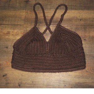 Brun stickad topp med smala axelband - Säljer en superfin brun stickad topp med smala axelband. Toppen är ärmlös och har en tight passform, perfekt för sommaren eller en fest. Den är handgjord och väldigt bekväm att bära. Passar perfekt till ett par höga jeans eller en kjol. 🌟