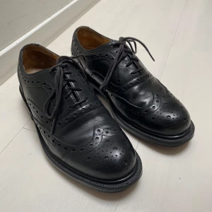 Snörskor - Snörskor i svart läder med brogue-mönster, storlek 40. Skorna är sparsamt använda och i bra skick. Fraktas eller möts upp i Stockholm!