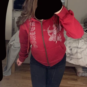 Röd hoodie med dragkedja och mönster - Säljer en snygg röd kofta med ett coolt mönster på framsidan. Den har långa ärmar och en normal passform. Perfekt för höst och vinter! storlek Xs men passar även S. märket laviago
