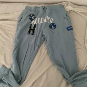 Ljusblå mjukisbyxor från Hoodrich - Säljer ett par ljusblå mjukisbyxor från Hoodrich i storlek L. Byxorna har flera coola patches och broderade detaljer, inklusive texten 'Hoodrich' och olika loggor. De är superbekväma och perfekta för en avslappnad stil. Passar perfekt för chill eller träning. Köp direkt eller ge prisförslag 💙 Pris kan sänkas vis snabbaffär