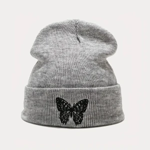 Grå stickad mössa med fjärilsmotiv - Säljer en snygg grå stickad mössa med ett svart fjärilsmotiv på framsidan. Mössan är perfekt för kalla dagar och har en ribbad kant som gör att den sitter bra på huvudet. Den är både stilren och bekväm, och passar till de flesta outfits. Perfekt för höst och vinter!