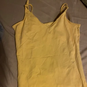 Gul ärmlös linnetopp - Säljer en enkel och bekväm gul linnetopp. Toppen är ärmlös och har blivit knappt använt på år.