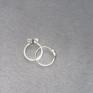 Två silverringar med tärnings- och blomdetaljer - Säljer två snygga silverringar. Den ena har en cool tärningsdetalj och den andra har en vacker fjäril. Perfekta för att ge din outfit en unik touch! 💍✨