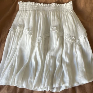 Vit kort kjol  - Säljer min vita kjol med påsydda blommor i storlek 34🤗🌸slutar strax ovanför knäna. Inköpt i USA, för 1 år sedan. Nypris cirka 500kr Jättefint skick 🌸 