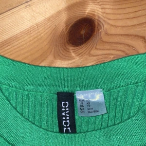 Grön ribbad ärmlös topp från Divided - Säljer en snygg grön ribbad topp från Divided. Den är ärmlös och perfekt för sommaren. Toppen är i storlek XS och sitter tight. Perfekt för både vardag och fest!