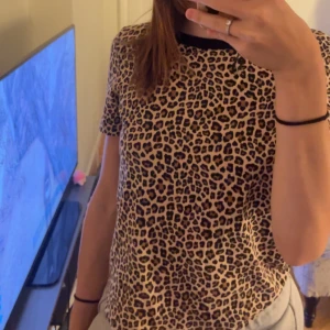 Leopardmönstrad topp från Divided - Säljer en snygg leopardmönstrad topp från Divided. Den är kortärmad och har en tight passform. Materialet är mjukt och bekvämt, troligen bomull eller en bomullsblandning. Toppen är i ny skick!