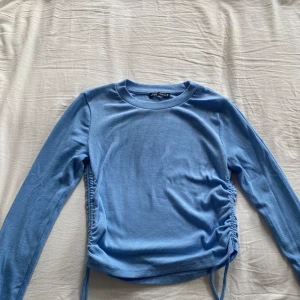 Ljusblå ribbad tröja från Zara - Säljer en superfin ljusblå tröja från Zara. Den är ribbad och har långa ärmar. Tröjan har en snygg detalj med snörning på sidorna. Perfekt för både vardag och fest! 💙