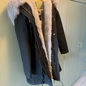 Jacka - Svart jacka med grå avtagbar päls. Mycket varm och är i fint skick.