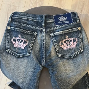 Victoria Beckham jeans med ljusrosa kronor - Victoria Beckham som jag säljer då de tyvärr inte satt som jag tänkt. Jag har sytt de lågmidjade och sprättat upp sömmarna vid benen (sista bilden) då de var väldigt korta på mig. Men går enkelt att sy tillbaka.  Midjemått: 35  Innerbenslängd: 72 
