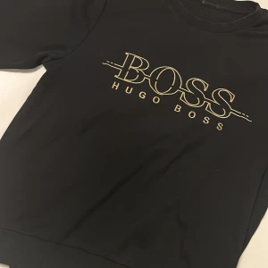 Hugo Boss - Sweatshirt (Svart & Guld) - Hugo Boss tjocktröja i helt perfekt skick. Säljs pga att den ej passar längre. Storlek: S 