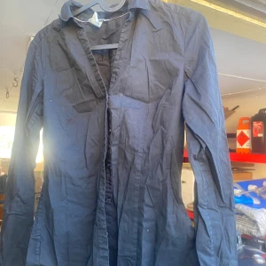 Svart skjorta från H&M - Säljer en svart långärmad skjorta från H&M. Den har en klassisk krage och knappar längs framsidan. Perfekt för både vardag och festliga tillfällen. Skjortan är i bomull och har en normal passform.