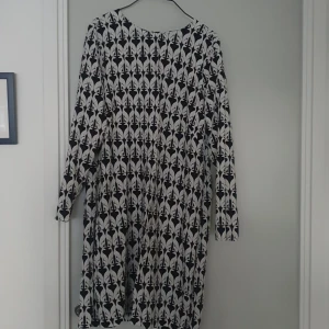 Svartvit mönstrad klänning - Säljer en superfin svartvit klänning /tunika med ett unikt mönster av stiliserade djur. Klänningen har långa ärmar och en bekväm passform. 