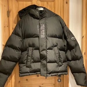 Svart pufferjacka från Trapstar - Säljer en svart pufferjacka från Trapstar med broderad text. Jackan är perfekt för vintern. Jackan är i nyskick och aldrig använd. Säljer då den är för stor.